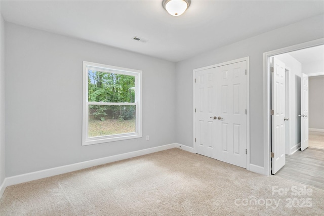 unfurnished bedroom featuring light carpet and a closet