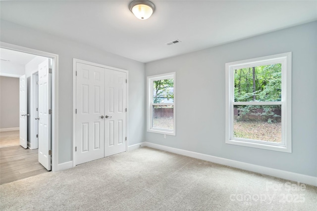 unfurnished bedroom featuring a closet, light carpet, and multiple windows