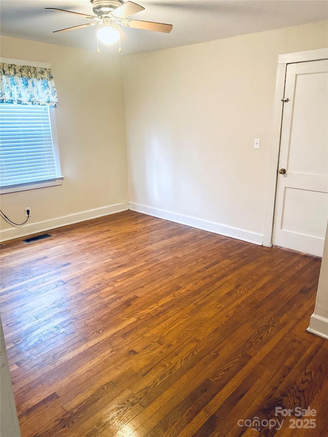 empty room with dark hardwood / wood-style floors and ceiling fan