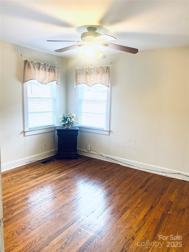 empty room with dark wood-type flooring and ceiling fan