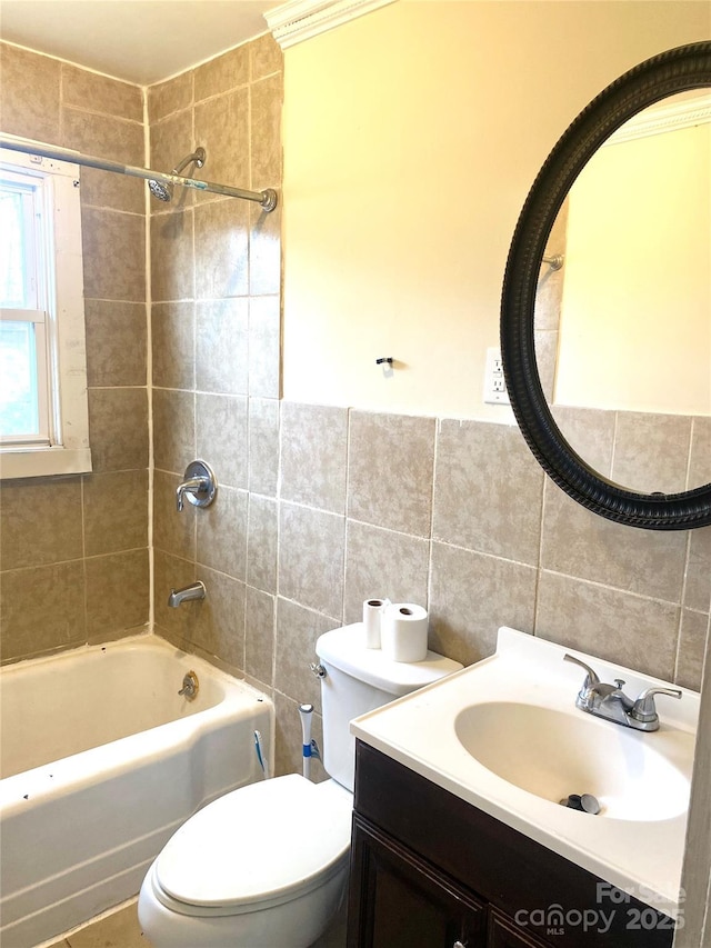 full bathroom featuring tiled shower / bath, vanity, toilet, and tile walls