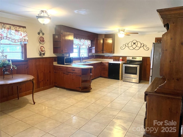 kitchen with sink, ceiling fan, appliances with stainless steel finishes, light tile patterned flooring, and wood walls