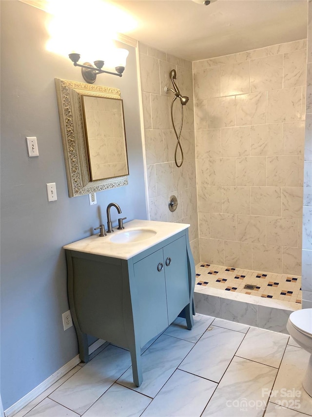 bathroom featuring a tile shower, vanity, and toilet