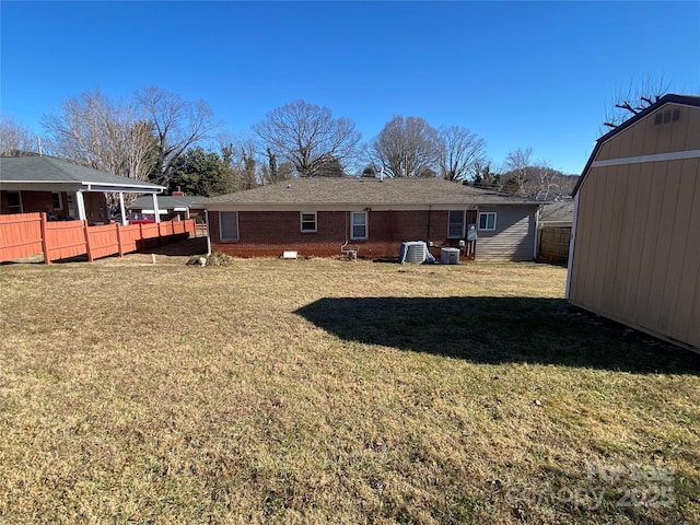 rear view of property featuring a yard, central AC, and a shed