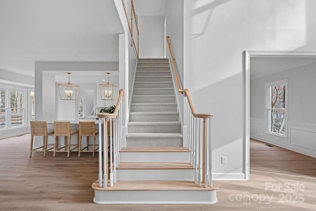 stairs with hardwood / wood-style flooring and an inviting chandelier