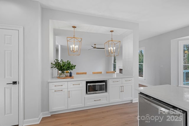 kitchen with white cabinetry, decorative light fixtures, light hardwood / wood-style floors, and appliances with stainless steel finishes