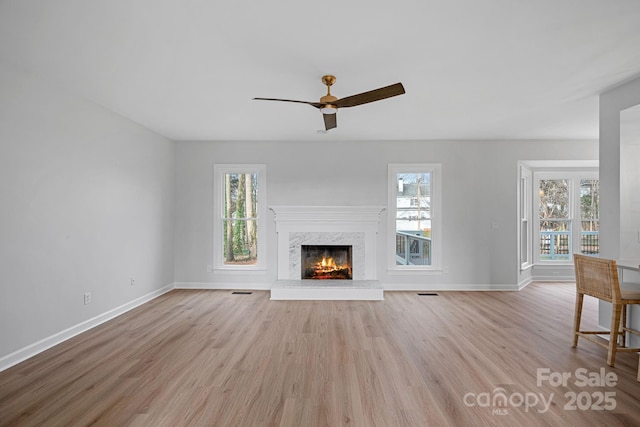 unfurnished living room featuring plenty of natural light, a fireplace, and light hardwood / wood-style flooring