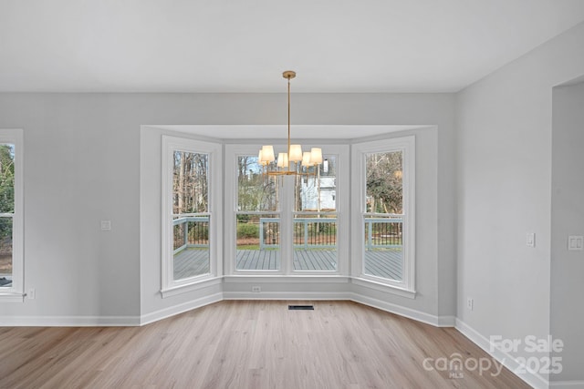 unfurnished dining area with an inviting chandelier and light hardwood / wood-style flooring