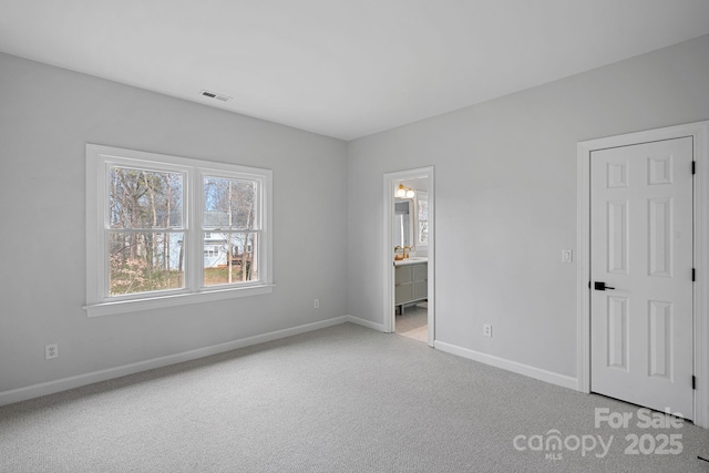 unfurnished bedroom with connected bathroom and light colored carpet