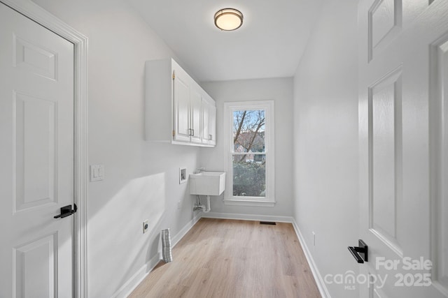 laundry area with cabinets, washer hookup, hookup for an electric dryer, and light wood-type flooring