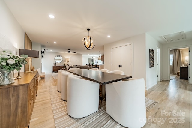 dining space with ceiling fan with notable chandelier and light hardwood / wood-style floors