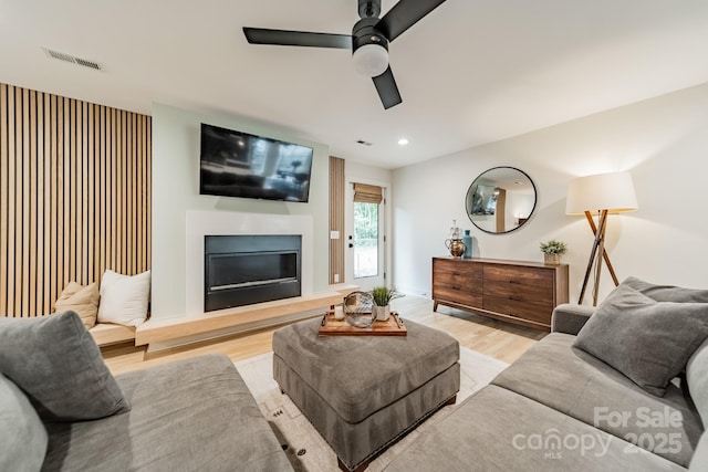 living area with recessed lighting, a ceiling fan, visible vents, light wood-style floors, and a glass covered fireplace