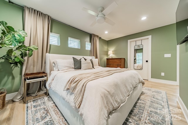 bedroom with multiple windows, baseboards, and wood finished floors