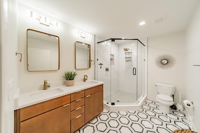 bathroom with toilet, a shower stall, double vanity, and a sink