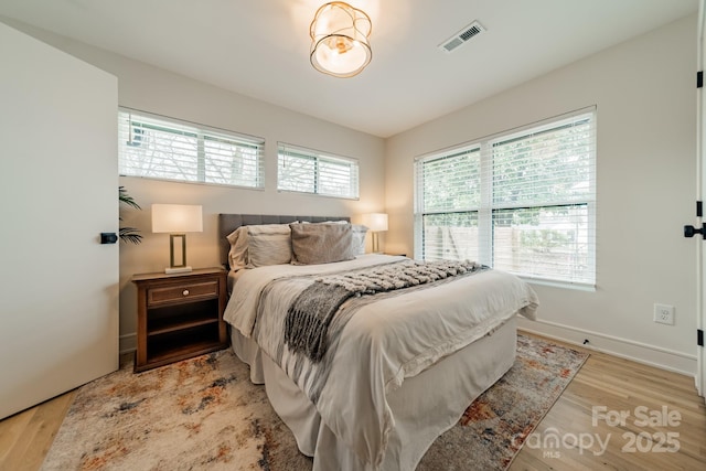 bedroom featuring light wood-style floors, baseboards, and visible vents