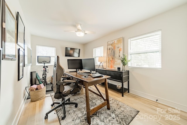 office area with light wood finished floors, a ceiling fan, and baseboards