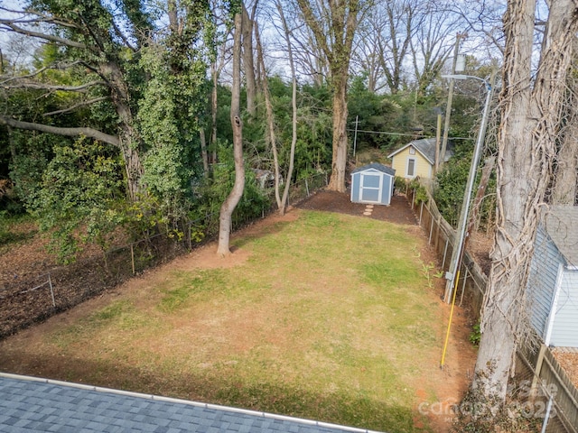 view of yard featuring a fenced backyard, an outdoor structure, and a shed