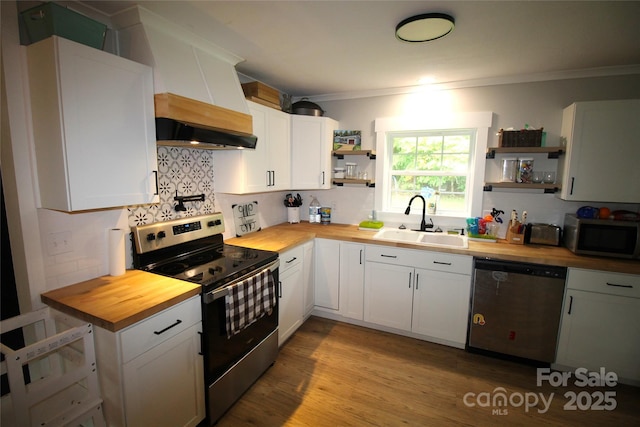 kitchen featuring white cabinetry, stainless steel appliances, butcher block counters, and sink