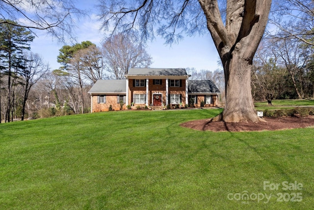 greek revival inspired property with a front yard and brick siding