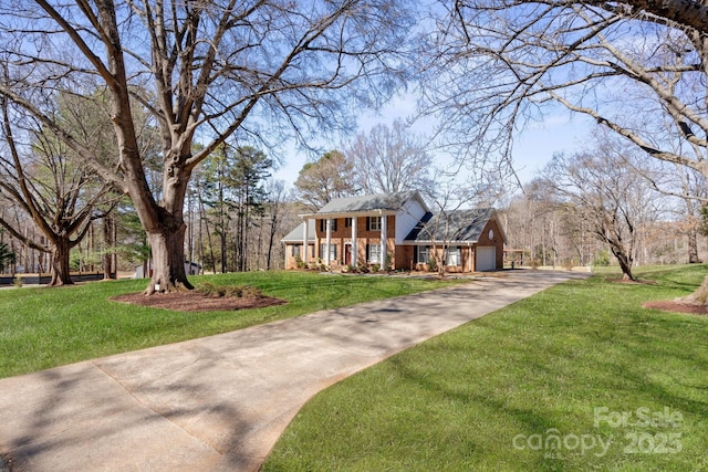 view of front of property with an attached garage, brick siding, driveway, and a front lawn