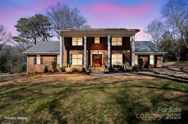 neoclassical / greek revival house featuring brick siding and a front lawn