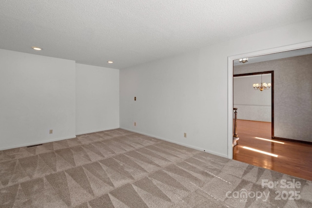 carpeted spare room featuring recessed lighting, visible vents, a textured ceiling, wood finished floors, and a chandelier