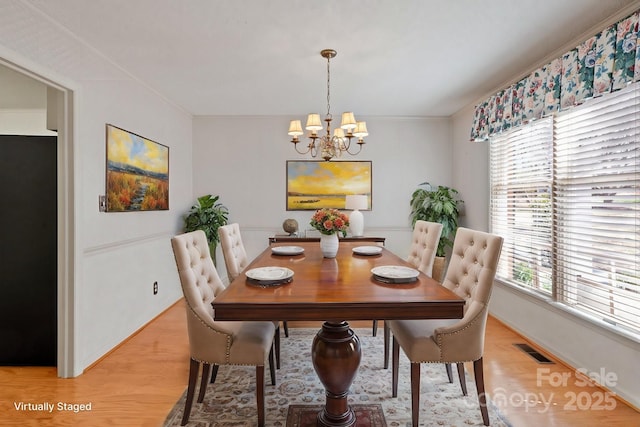 dining room featuring light wood-style floors, visible vents, crown molding, and an inviting chandelier