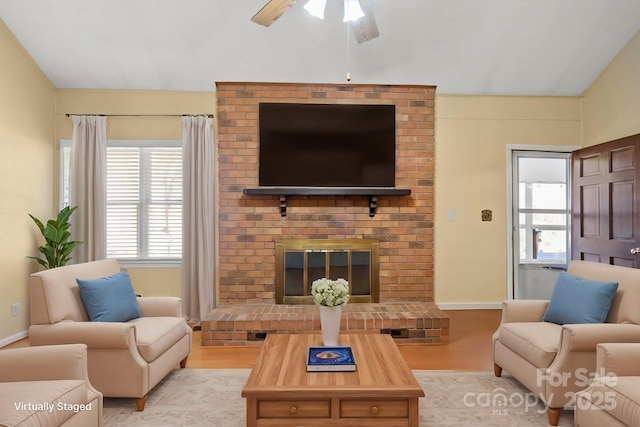 living area featuring vaulted ceiling, a brick fireplace, wood finished floors, and baseboards