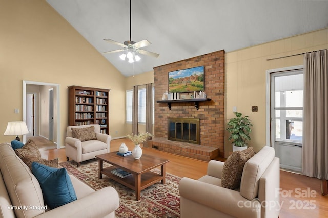 living room featuring ceiling fan, high vaulted ceiling, a fireplace, and wood finished floors