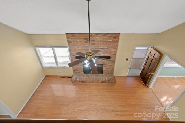 unfurnished living room featuring a ceiling fan, visible vents, baseboards, and wood finished floors