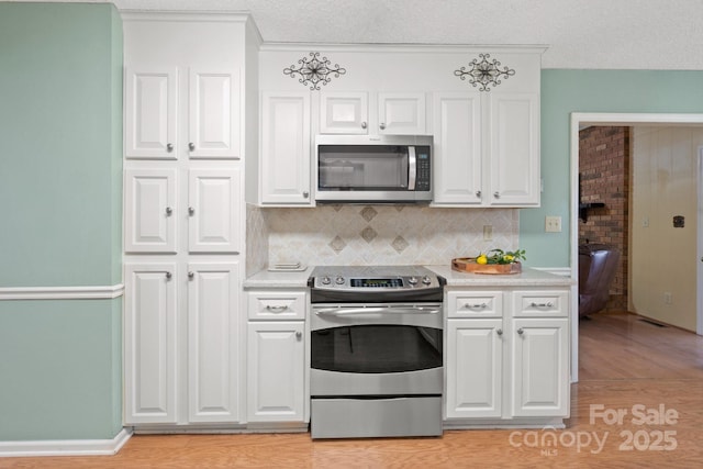 kitchen with light wood finished floors, light countertops, appliances with stainless steel finishes, and white cabinetry