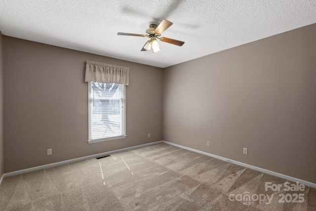 carpeted empty room featuring baseboards, a textured ceiling, visible vents, and a ceiling fan