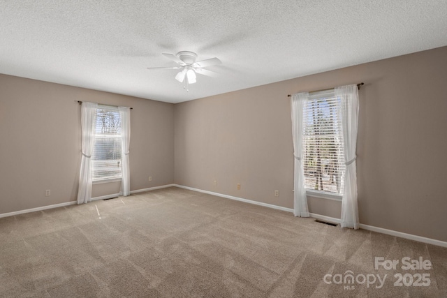 spare room with baseboards, visible vents, a ceiling fan, a textured ceiling, and carpet flooring