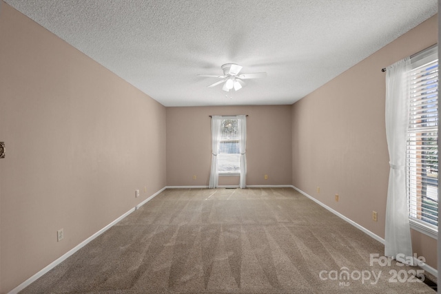 carpeted empty room with ceiling fan, baseboards, and a textured ceiling