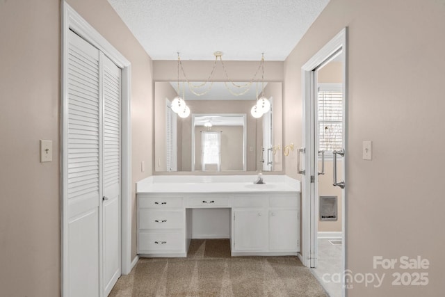 bathroom with a textured ceiling, a closet, vanity, and a wealth of natural light