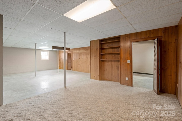 below grade area featuring a paneled ceiling and wooden walls