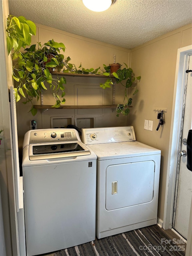 laundry room with dark hardwood / wood-style floors, washer and dryer, and a textured ceiling