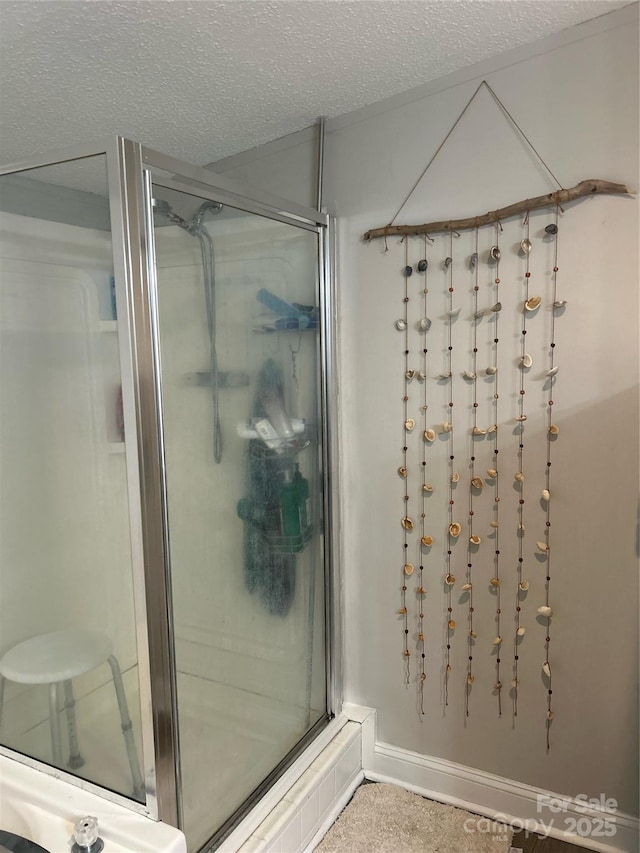 bathroom featuring a textured ceiling and a shower with shower door