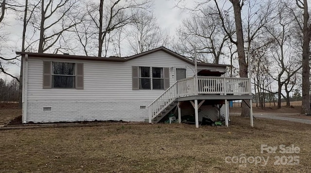 rear view of property featuring a wooden deck and a lawn