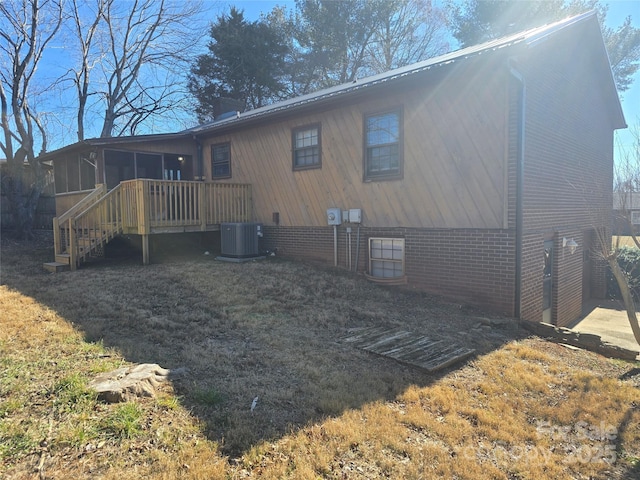 back of property with a lawn, a deck, a sunroom, and central air condition unit