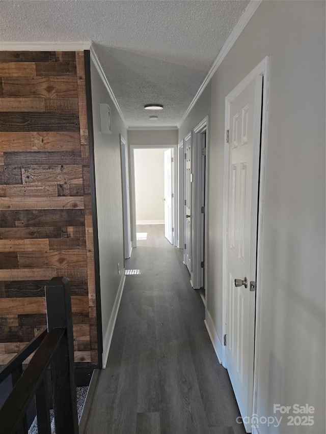 hallway featuring crown molding, dark wood-type flooring, and a textured ceiling