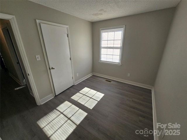 unfurnished bedroom with dark wood-type flooring and a textured ceiling