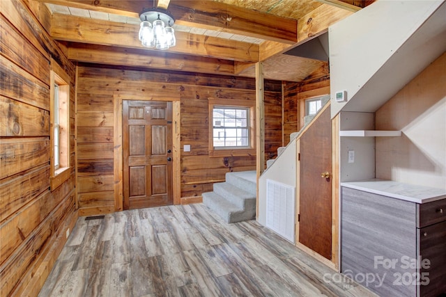 foyer with light hardwood / wood-style flooring, wooden ceiling, beamed ceiling, and wood walls