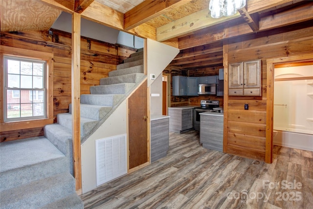 staircase featuring hardwood / wood-style floors, wooden walls, and beamed ceiling