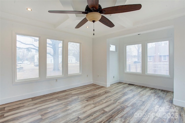 unfurnished room featuring coffered ceiling, plenty of natural light, light hardwood / wood-style floors, and beamed ceiling