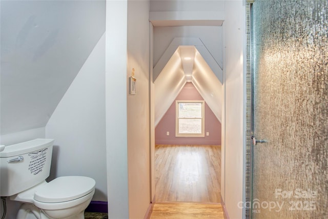 bathroom featuring hardwood / wood-style flooring, vaulted ceiling, and toilet