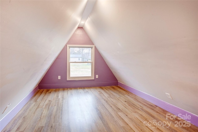 additional living space featuring vaulted ceiling and light hardwood / wood-style floors