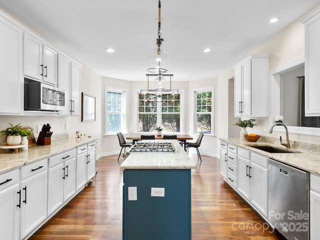 kitchen featuring sink, white cabinetry, stainless steel appliances, a center island, and light stone countertops