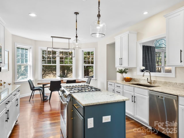 kitchen featuring a kitchen island, decorative light fixtures, white cabinetry, sink, and stainless steel appliances