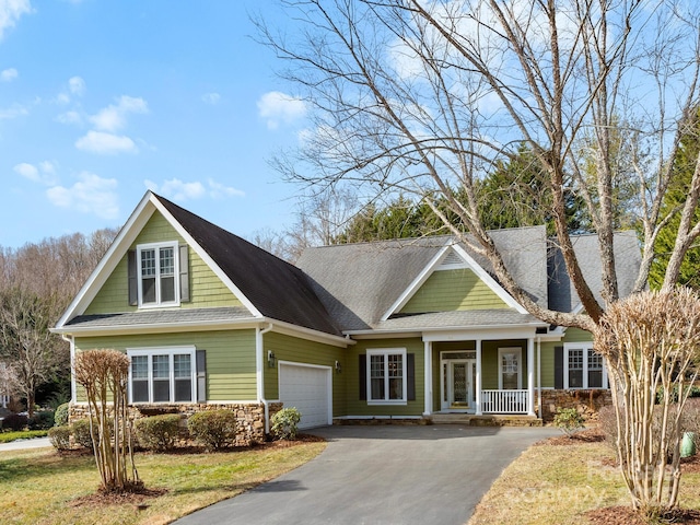 view of front facade featuring a porch, a garage, and a front lawn